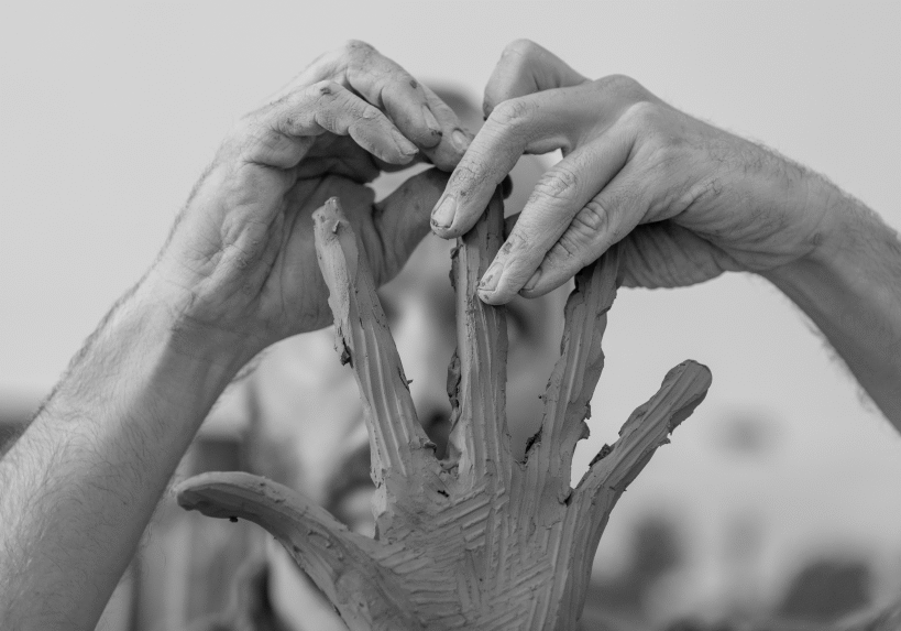 Black and white image of a man's hands sculpting hands