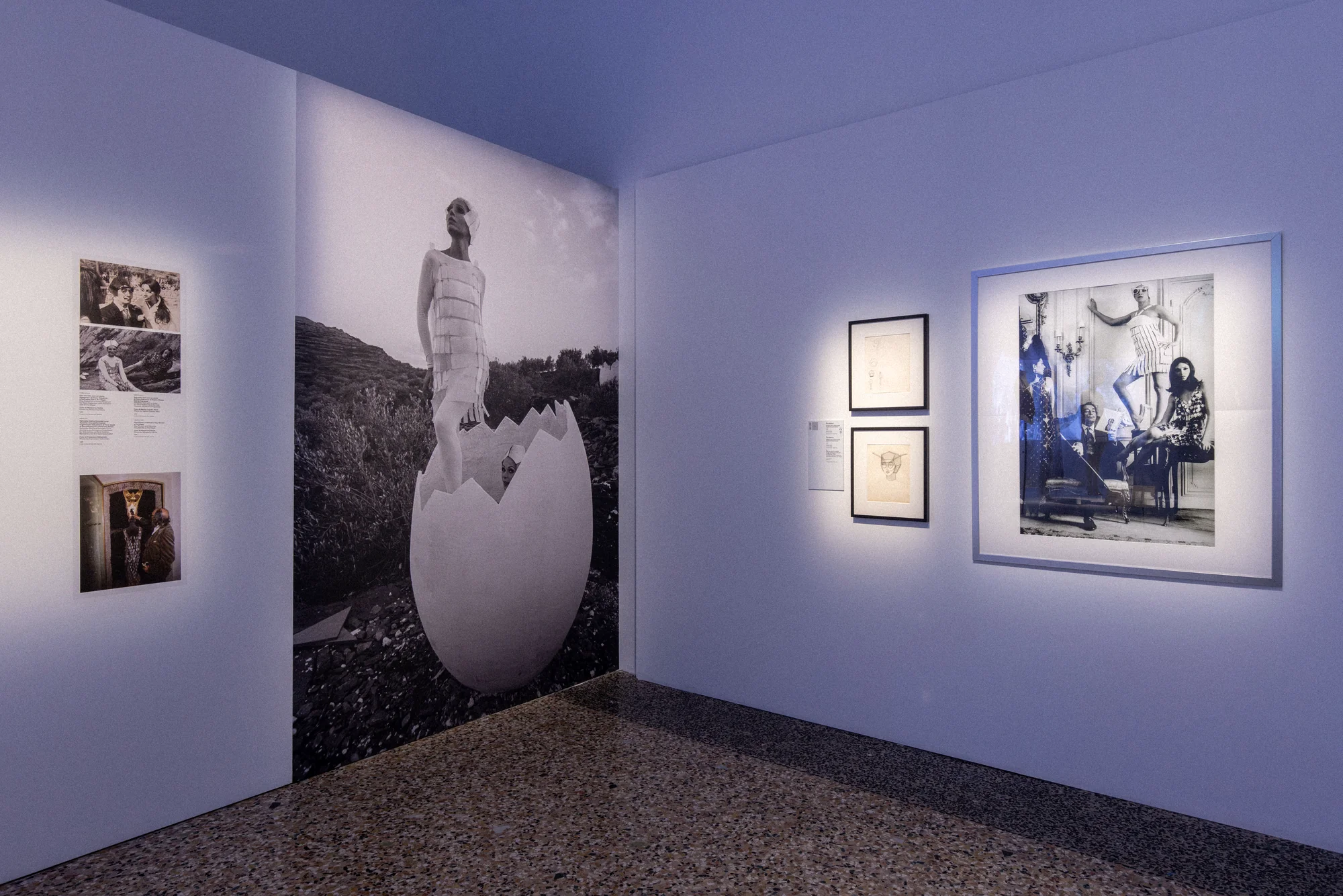 Gallery wall with a mural of a woman emerging from an egg and framed photographs