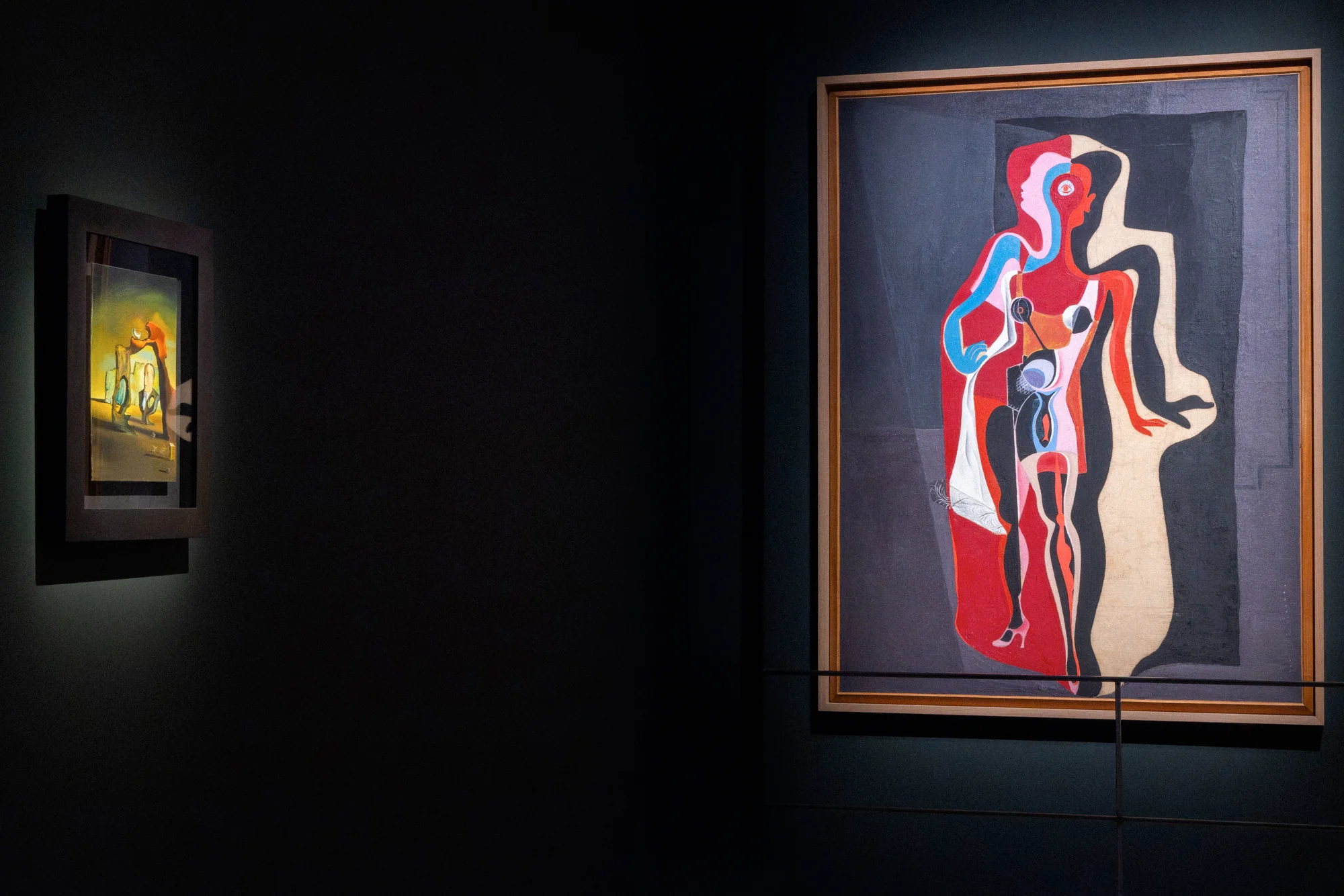 Large surrealist painting of a red and blue figure in a gilt frame, a smaller painting beside it
