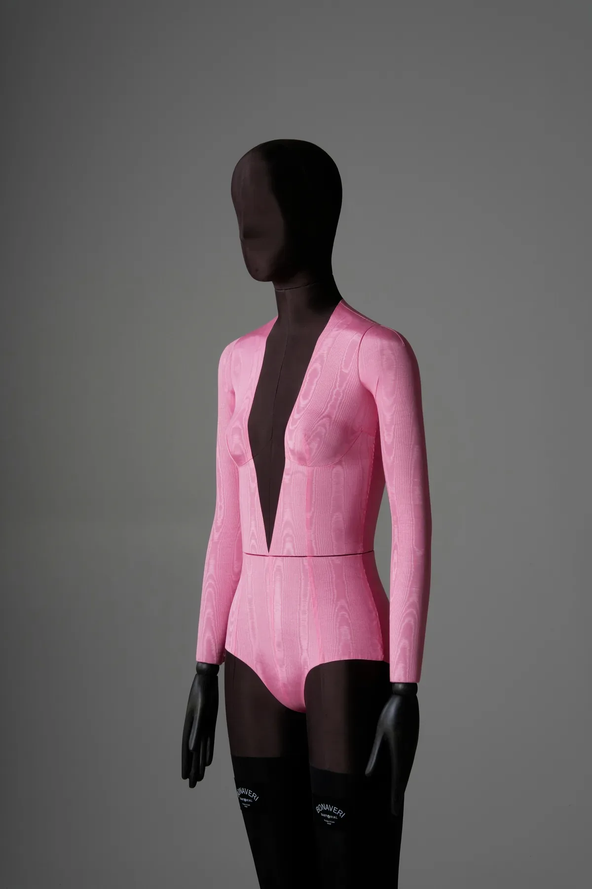 Three-quarter upper body view of the pink moire bodysuit bespoke mannequin showing the deep V-neckline and moire texture