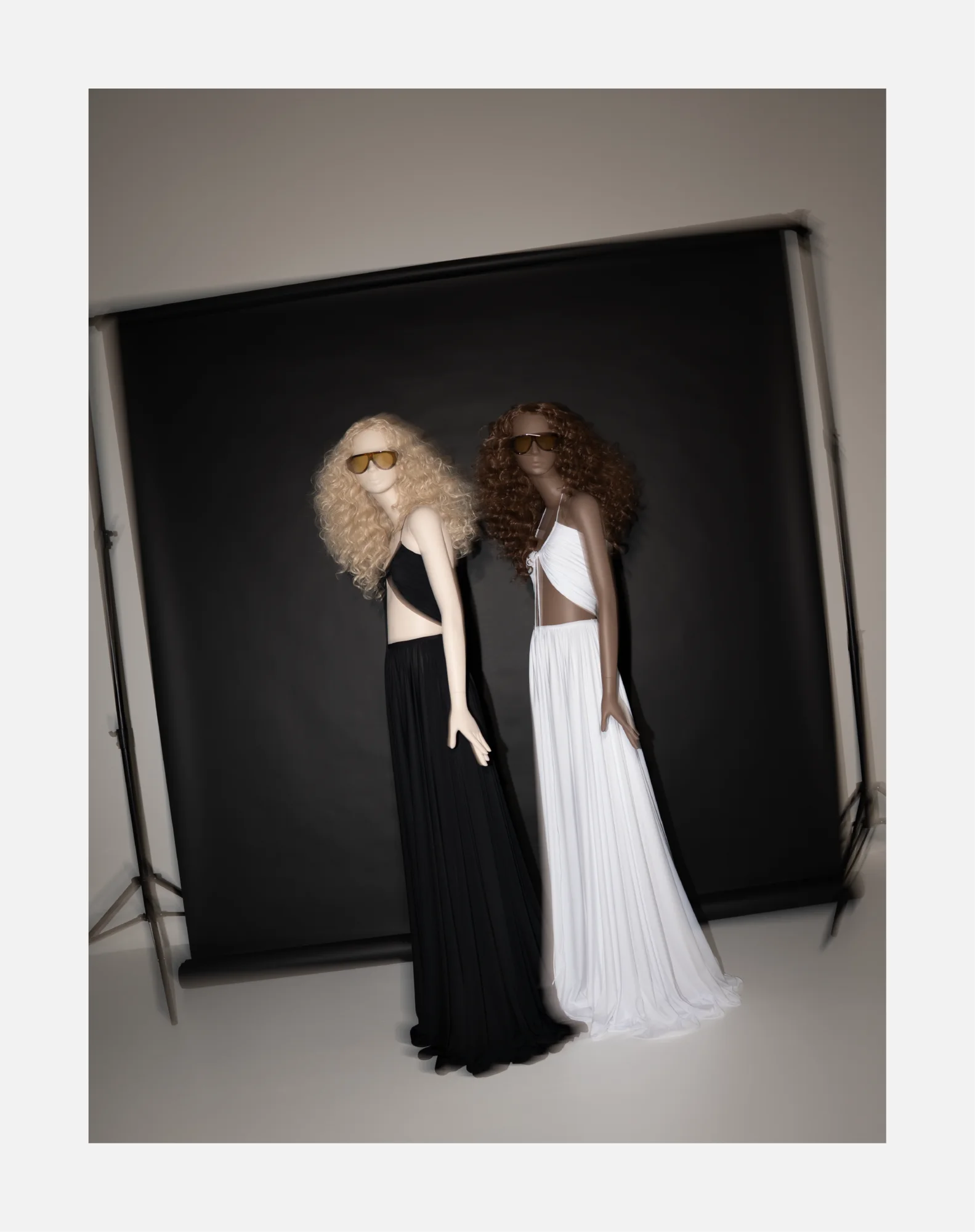 Two Obsession mannequins in black and white gowns in front of a black studio backdrop