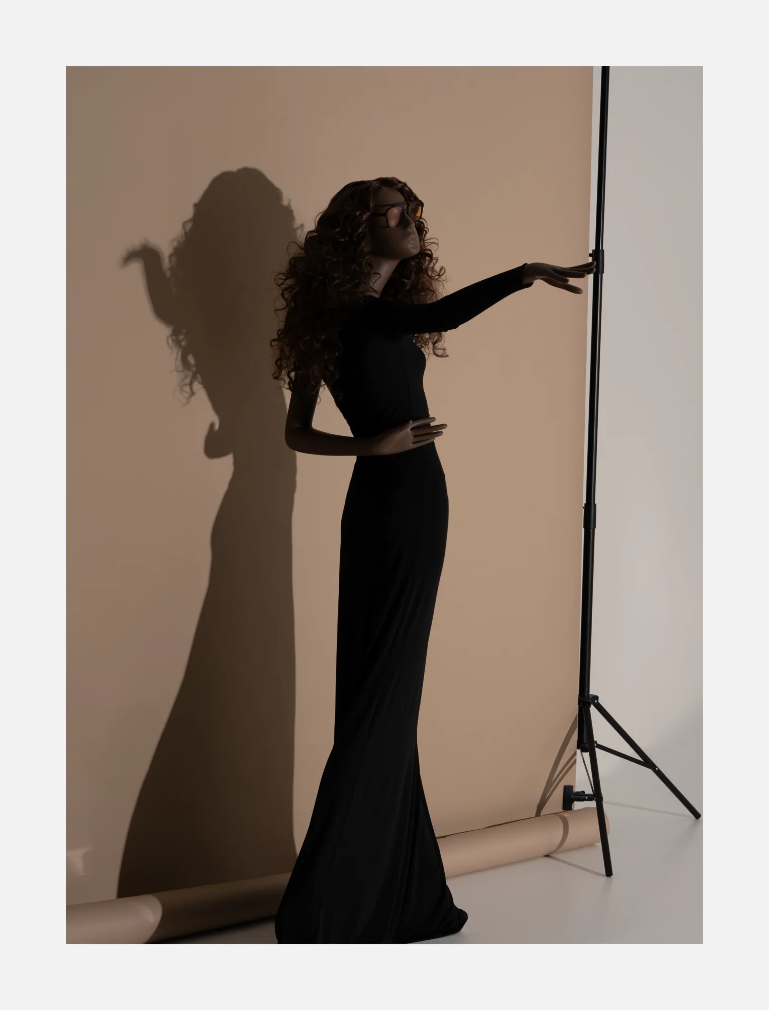 Obsession mannequin in a long black dress reaching towards a light stand