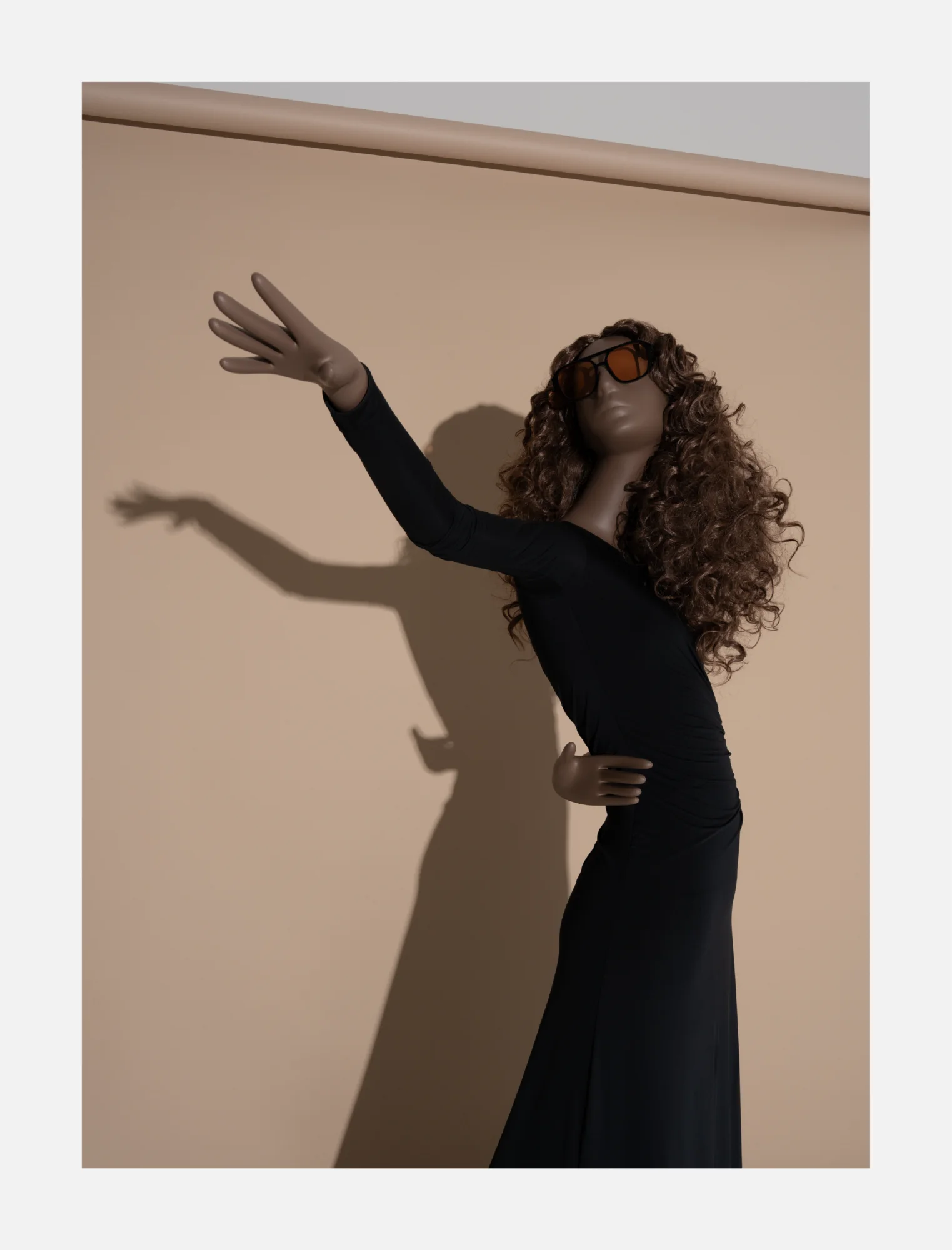 Obsession mannequin in a black dress with one arm raised, casting a shadow