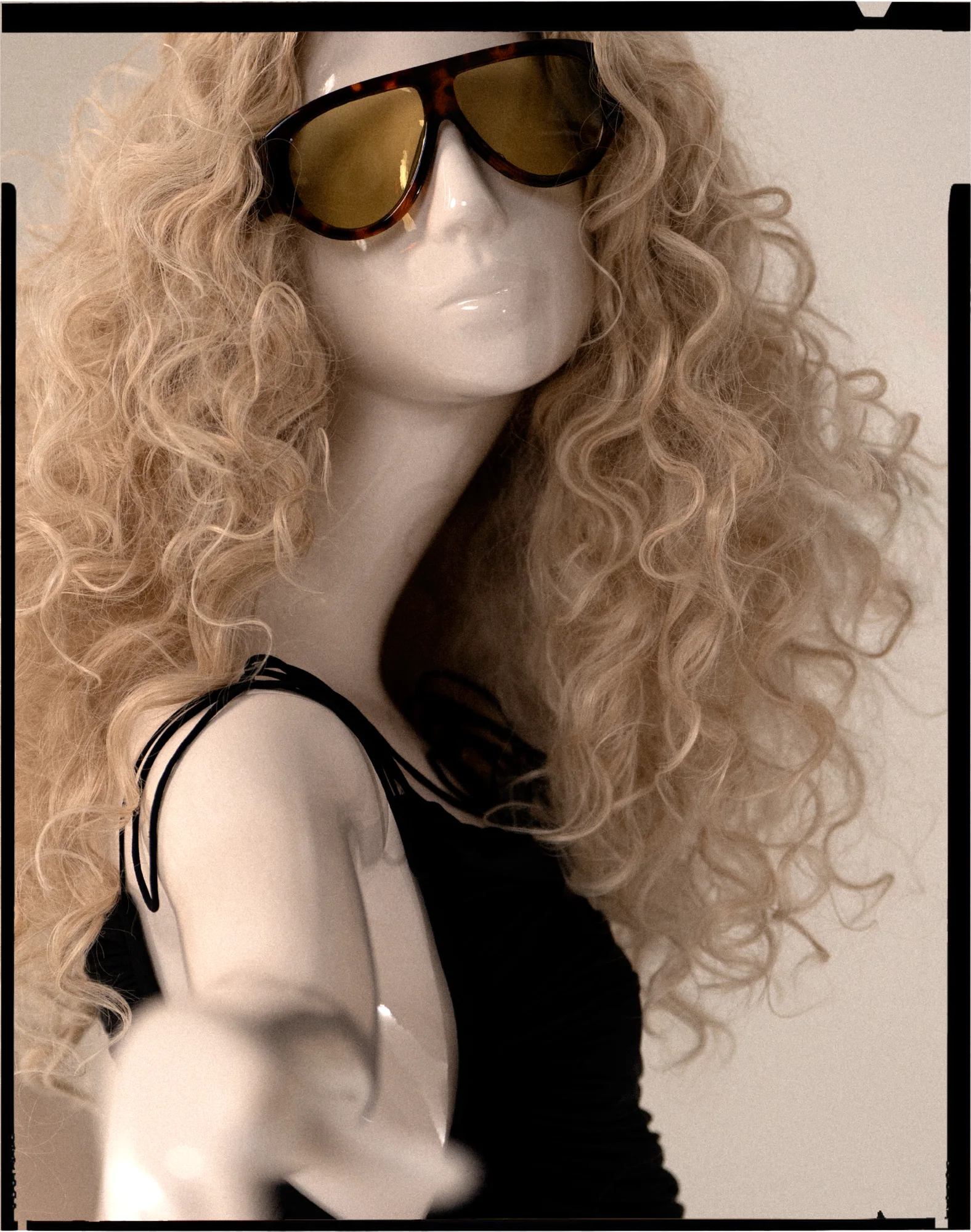 Gloss Obsession mannequin with a blonde curled wig, framed like a film negative