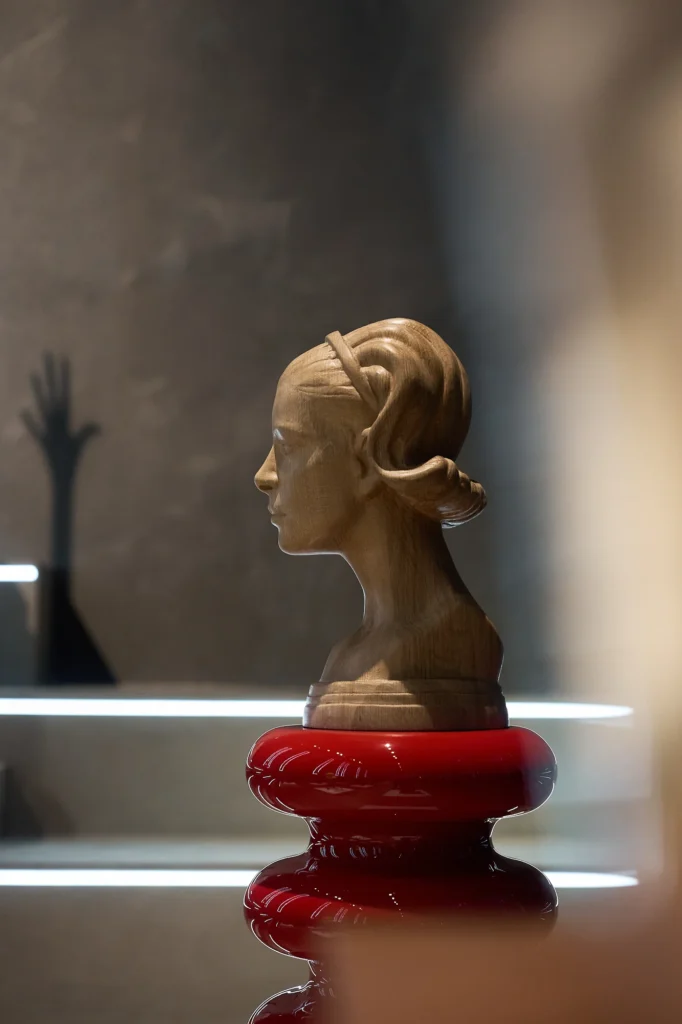 Sculpted bust with braided hair on a glossy red coiled base