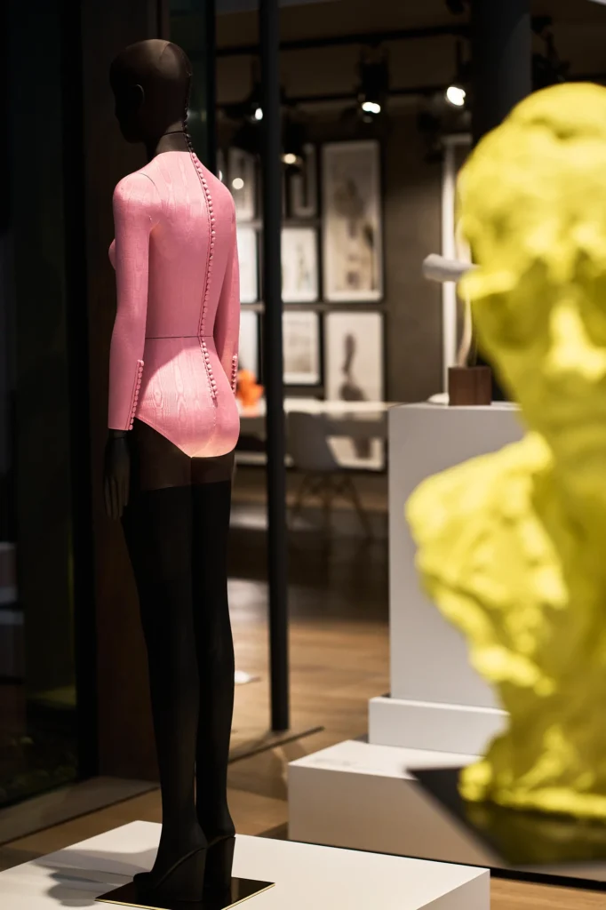 Mannequin in a pink jacket beside a yellow sculpted head