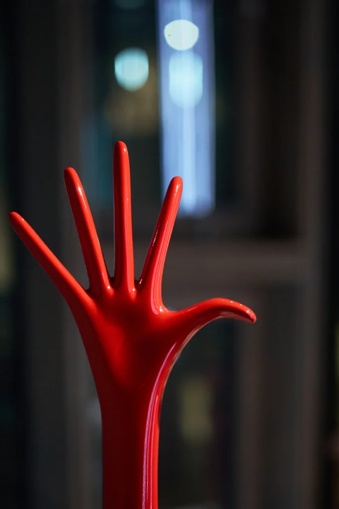 Glossy red hand sculpture against a dark background